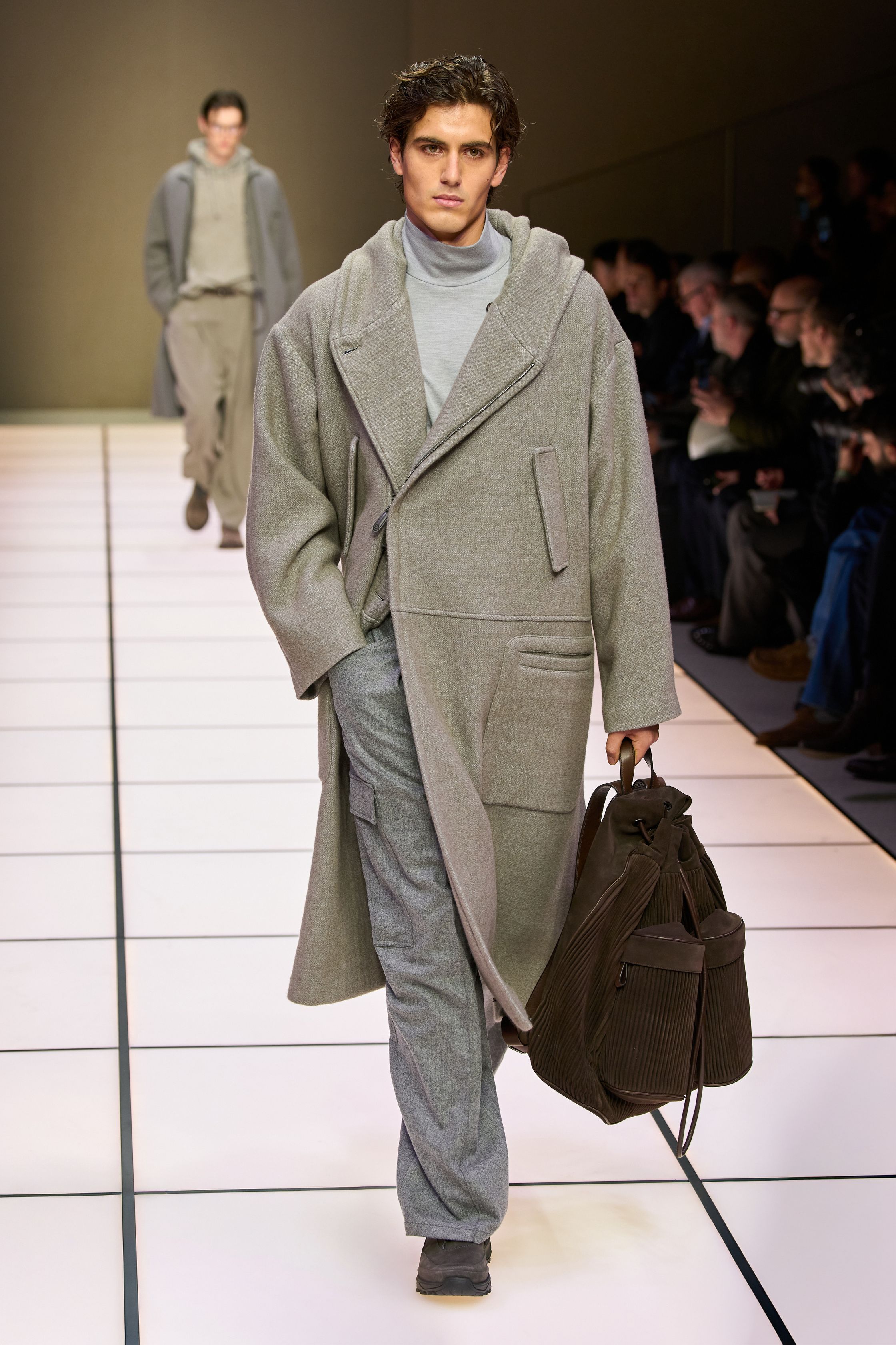 Giorgio Armani 26FW 男装回归品牌最本质的语言：流动、克制与永恒。柔软大衣、宽松长裤、针织与轻结构西装在灰、驼、米与墨绿中缓慢展开，强调身体与面料之间的自然关系。系列几乎不依赖任何戏剧化装饰，却通过比例、步伐与质感建立权威感，是对“真正优雅无需证明”的再次确认，也是一种对快节奏时尚的温和抵抗-顽石频道趋势研究